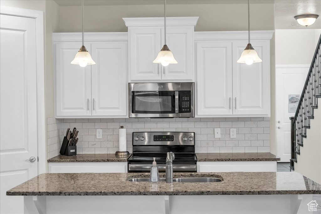 Kitchen with appliances with stainless steel finishes, tasteful backsplash, white cabinetry, and a sink