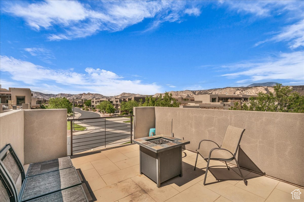 View of patio / terrace featuring an outdoor fire pit, a balcony, a mountain view, and a residential view
