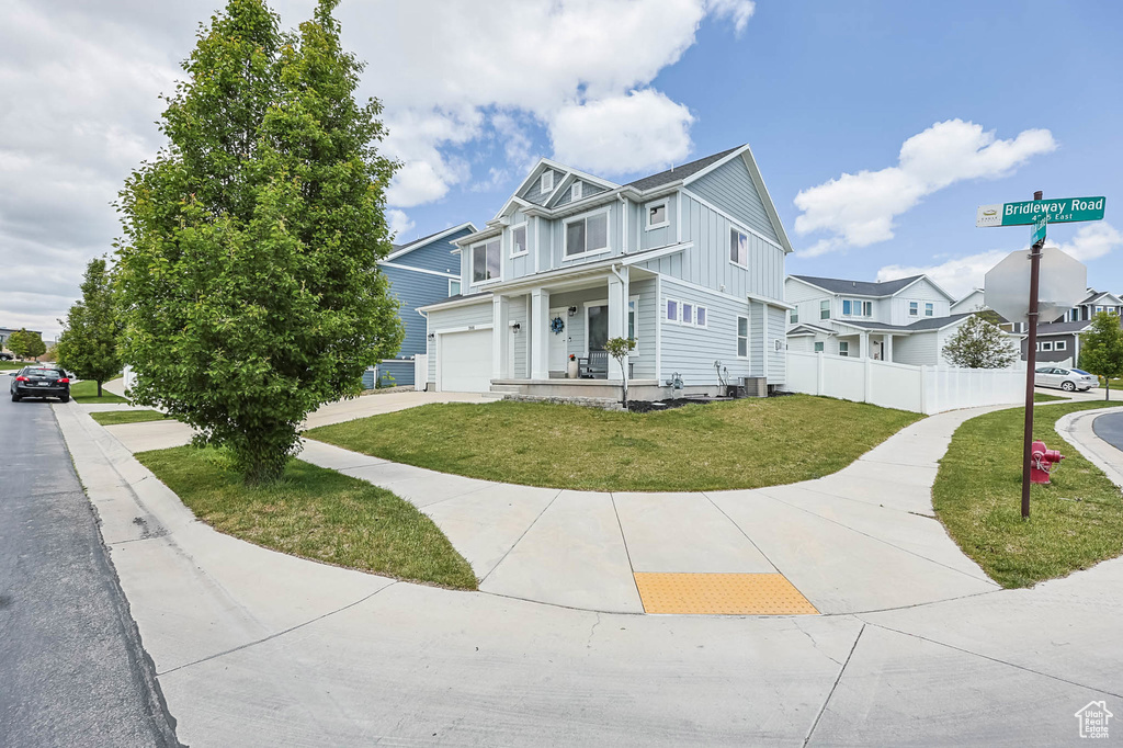 View of property with board and batten siding, cooling unit, driveway, and an attached garage