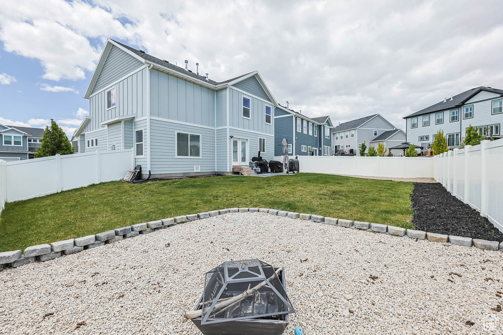 Rear view of house featuring board and batten siding, a fire pit, a residential view, and a patio area