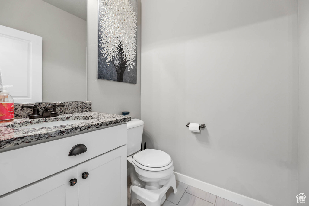 Half bath with toilet, baseboards, and vanity