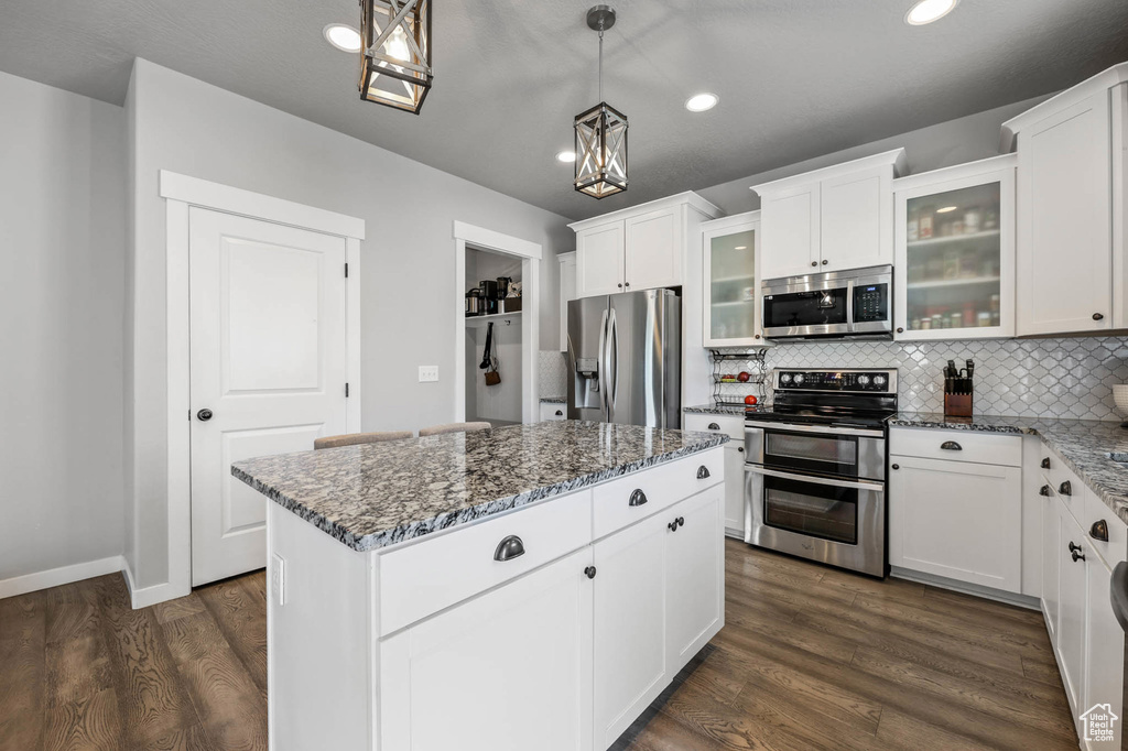 Kitchen featuring stainless steel appliances, recessed lighting, tasteful backsplash, dark stone counters, and dark wood-style floors