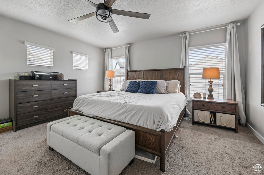 Carpeted bedroom with a textured ceiling and ceiling fan