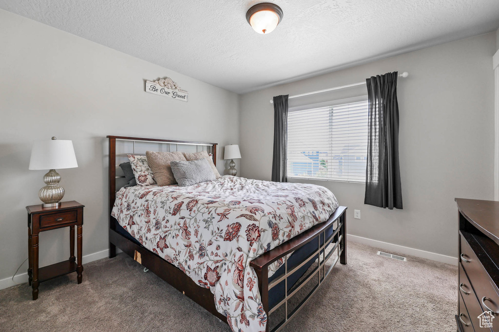 Carpeted bedroom featuring a textured ceiling and baseboards