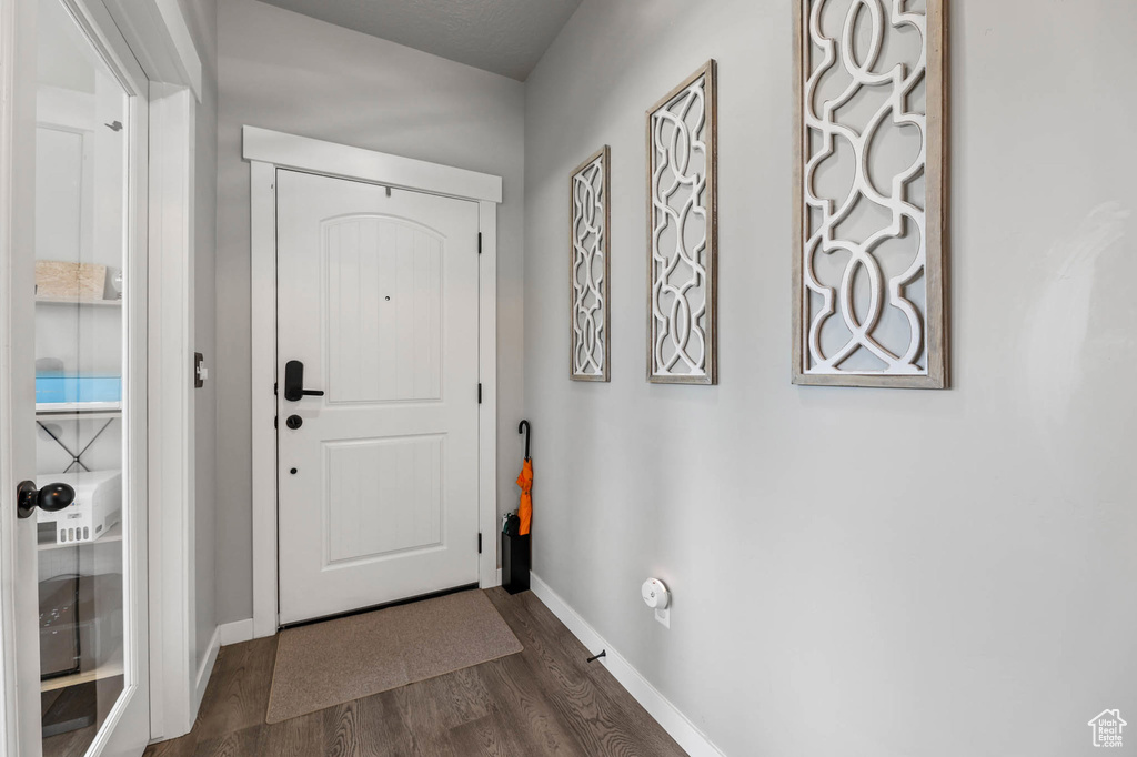 Doorway to outside featuring dark wood-type flooring and baseboards