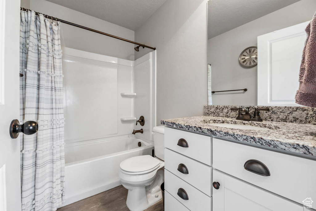Full bathroom with wood finished floors, toilet, shower / tub combo, and vanity