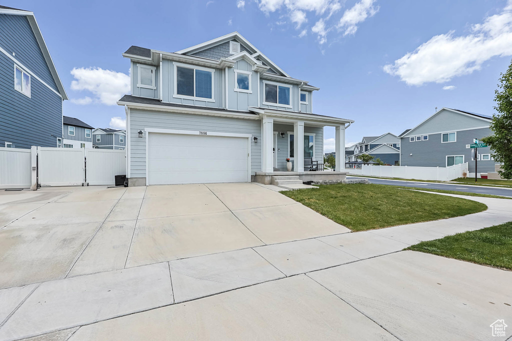 View of front of house featuring covered porch, an attached garage, board and batten siding, driveway, and a residential view