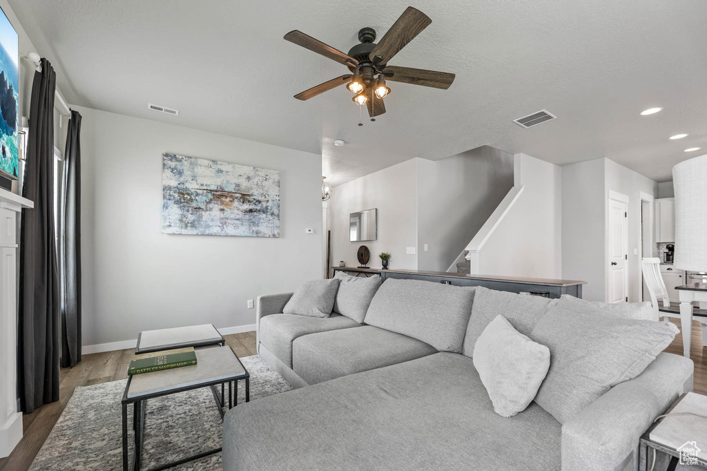 Living area with ceiling fan, wood finished floors, recessed lighting, baseboards, and stairway