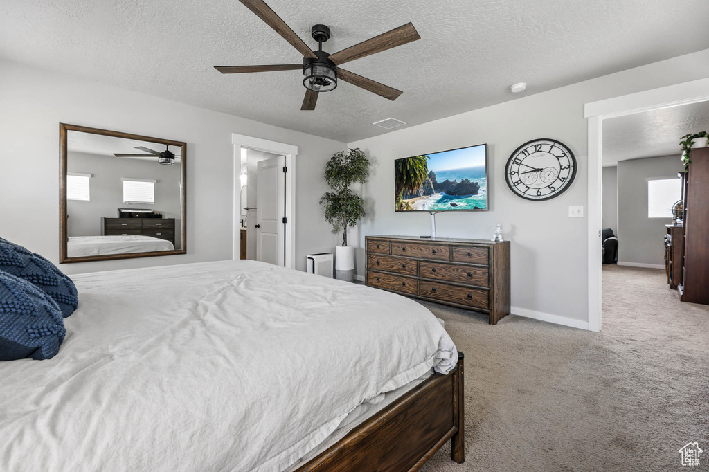 Carpeted bedroom with a textured ceiling, baseboards, and a ceiling fan