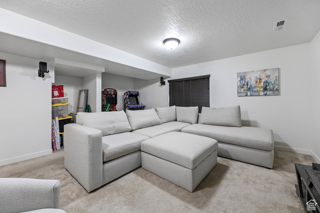 Living room with a textured ceiling, light carpet, and baseboards