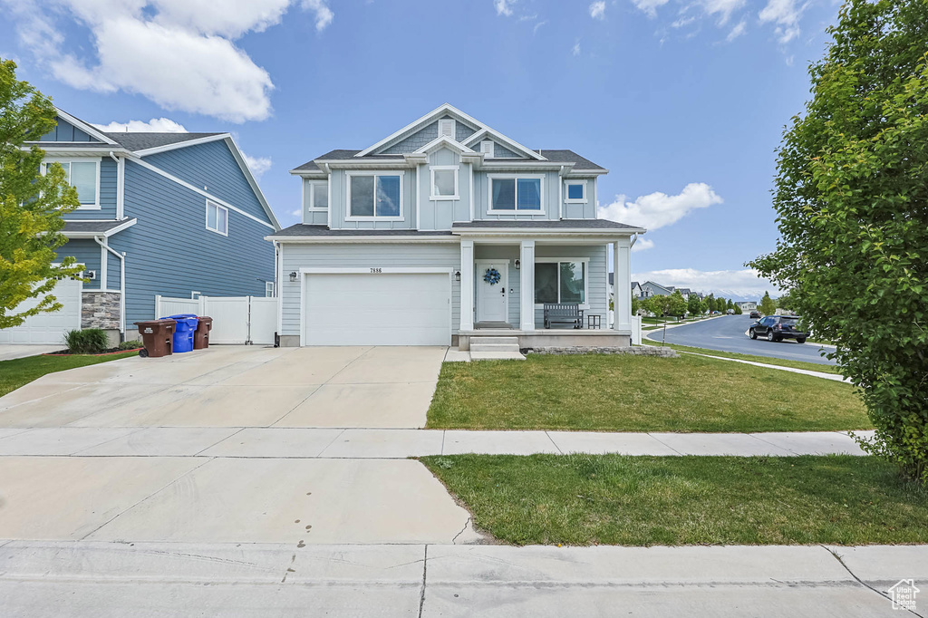 View of front of property with a porch, driveway, and an attached garage