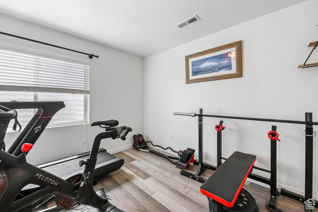 Workout area with wood finished floors, a textured ceiling, and baseboards