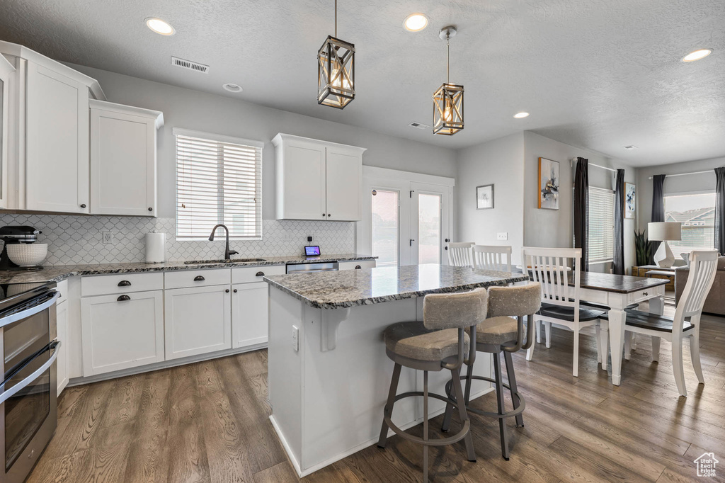 Kitchen featuring a sink, a center island, range with two ovens, tasteful backsplash, and healthy amount of natural light