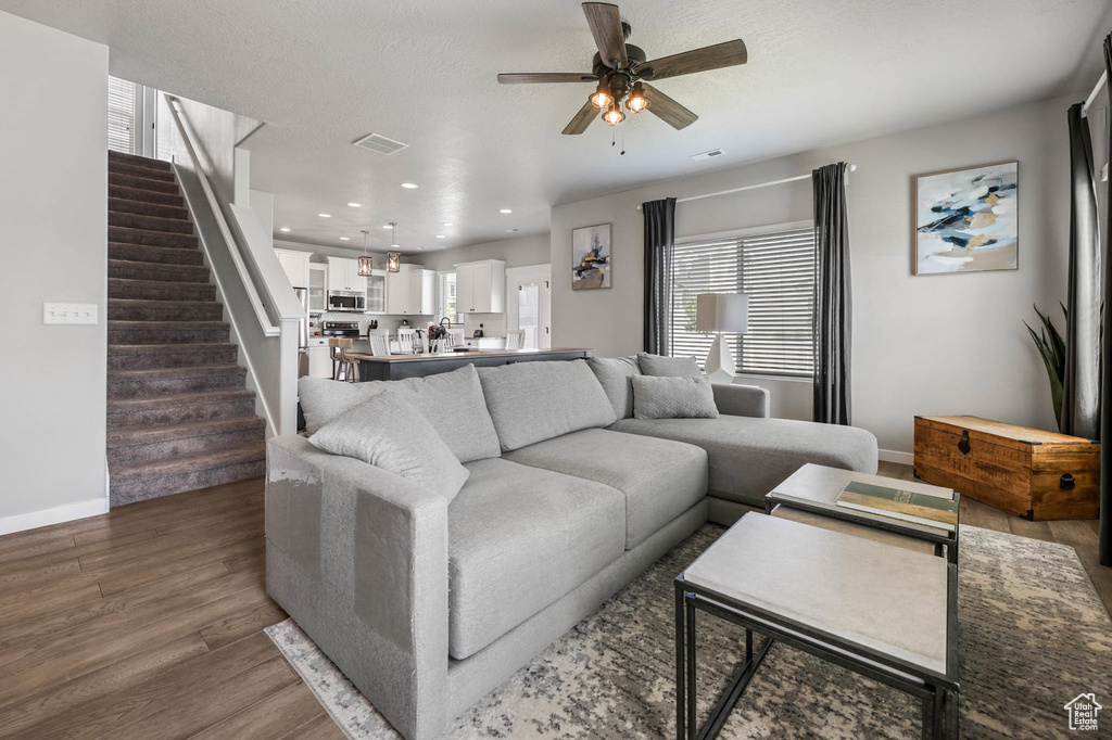 Living room with ceiling fan, stairs, healthy amount of natural light, dark wood-style flooring, and recessed lighting