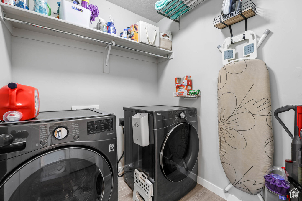 Laundry room with independent washer and dryer, wood finished floors, and baseboards
