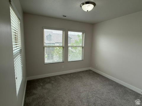 Carpeted spare room featuring baseboards