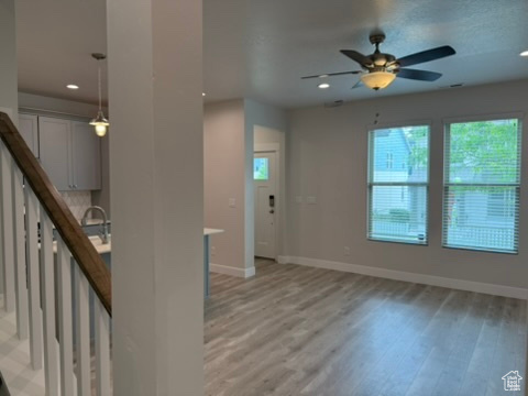 Unfurnished living room featuring healthy amount of natural light, light wood-style flooring, baseboards, and recessed lighting