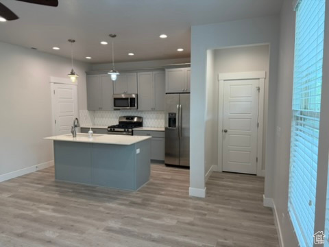 Kitchen featuring stainless steel appliances, gray cabinetry, ceiling fan, tasteful backsplash, and baseboards