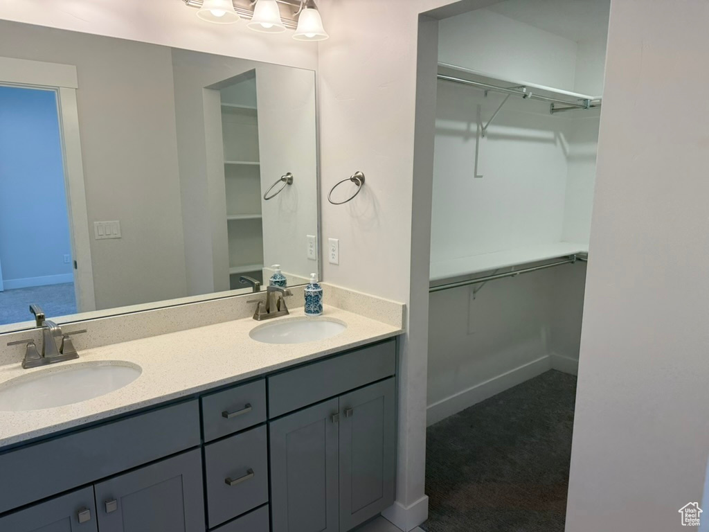 Full bath featuring double vanity, baseboards, and a walk in closet