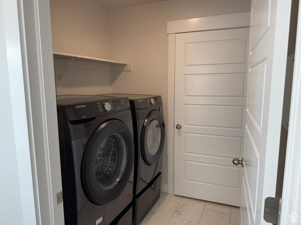 Laundry area featuring washer and dryer and light marble finish flooring