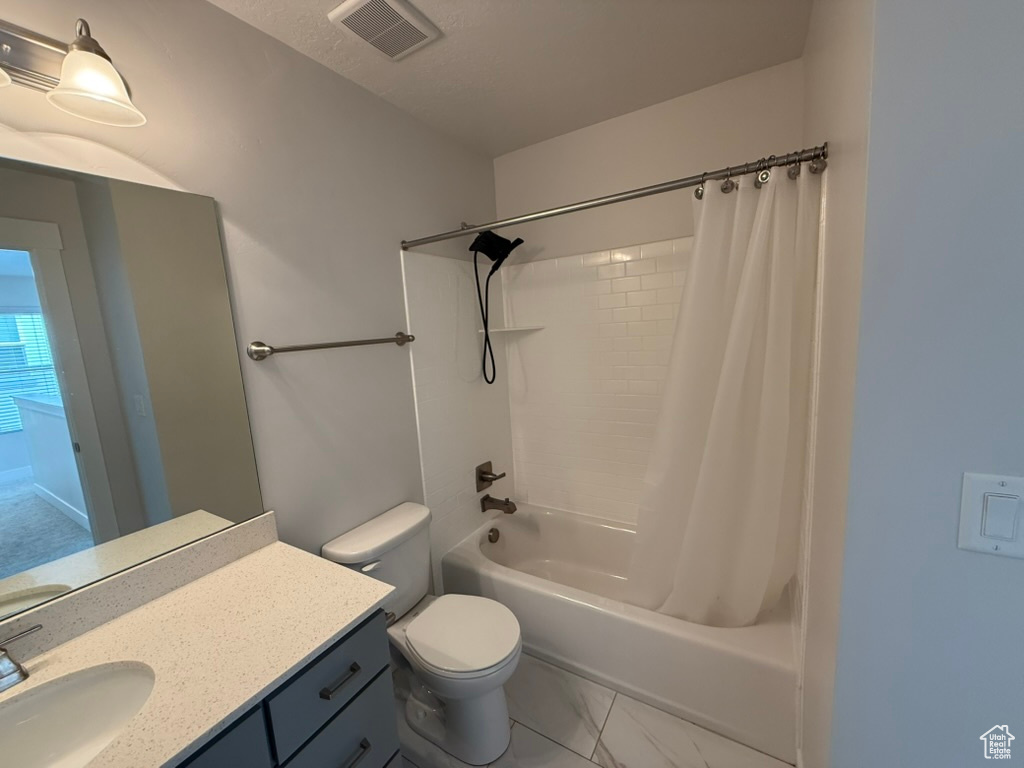 Full bathroom featuring toilet, vanity, marble look tiles, and shower / bath combination with curtain