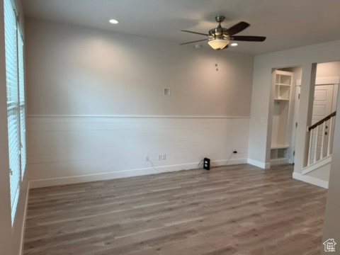 Unfurnished room with wood finished floors, a ceiling fan, recessed lighting, baseboards, and stairway