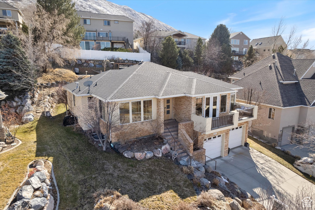 View of front of property featuring stone siding, an attached garage, concrete driveway, a front yard, and a residential view