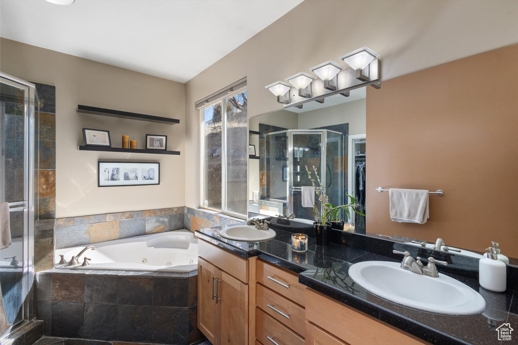 Full bath featuring a shower stall, a tub with jets, and double vanity