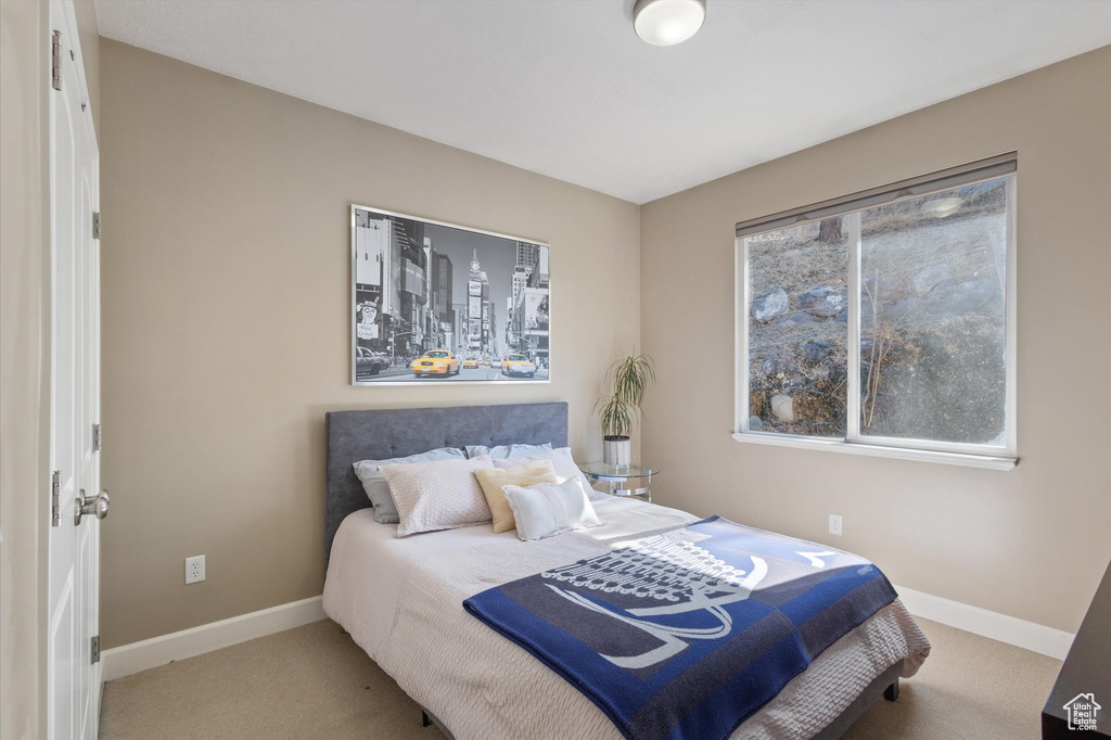 Carpeted bedroom featuring baseboards and multiple windows