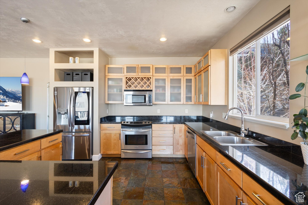 Kitchen featuring stainless steel appliances, a sink, healthy amount of natural light, glass insert cabinets, and recessed lighting