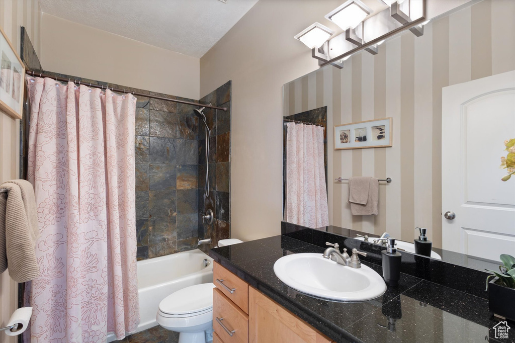 Full bath featuring toilet, vanity, and shower / tub combo