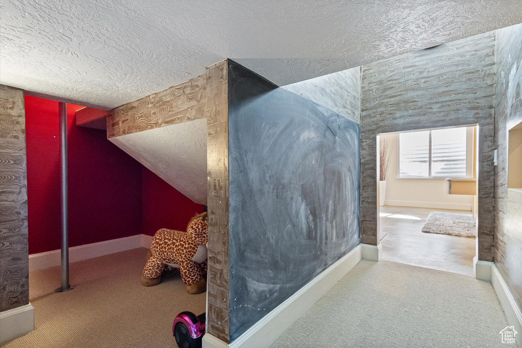 Additional living space with a textured ceiling, carpet floors, and baseboards