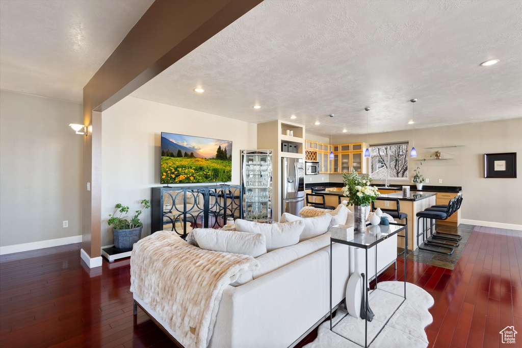 Living room featuring baseboards, dark wood-style flooring, recessed lighting, and a textured ceiling
