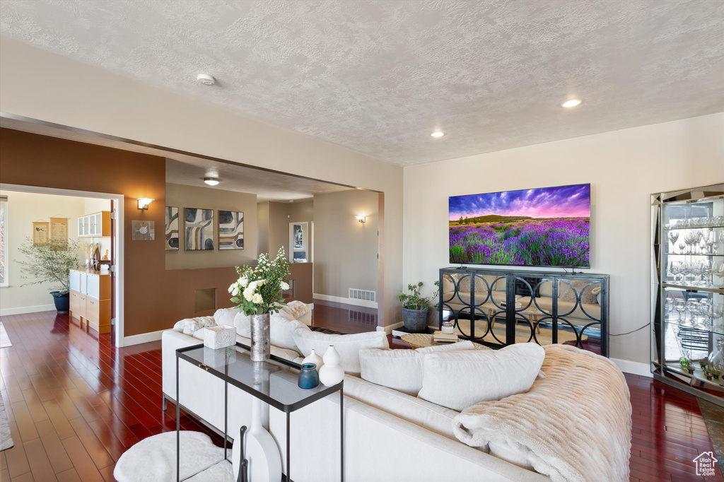 Living room with baseboards, dark wood-style flooring, a textured ceiling, recessed lighting, and plenty of natural light