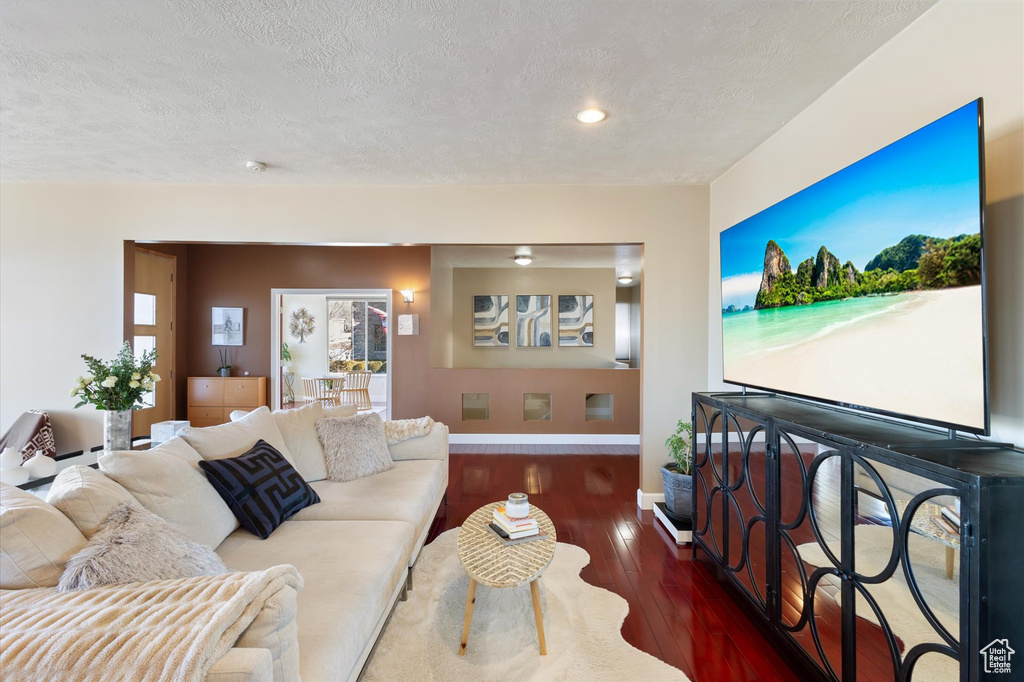 Living area with baseboards, wood finished floors, a textured ceiling, and recessed lighting