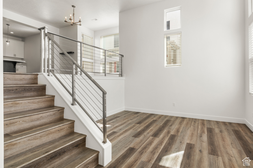 Stairway with baseboards, a chandelier, and wood finished floors