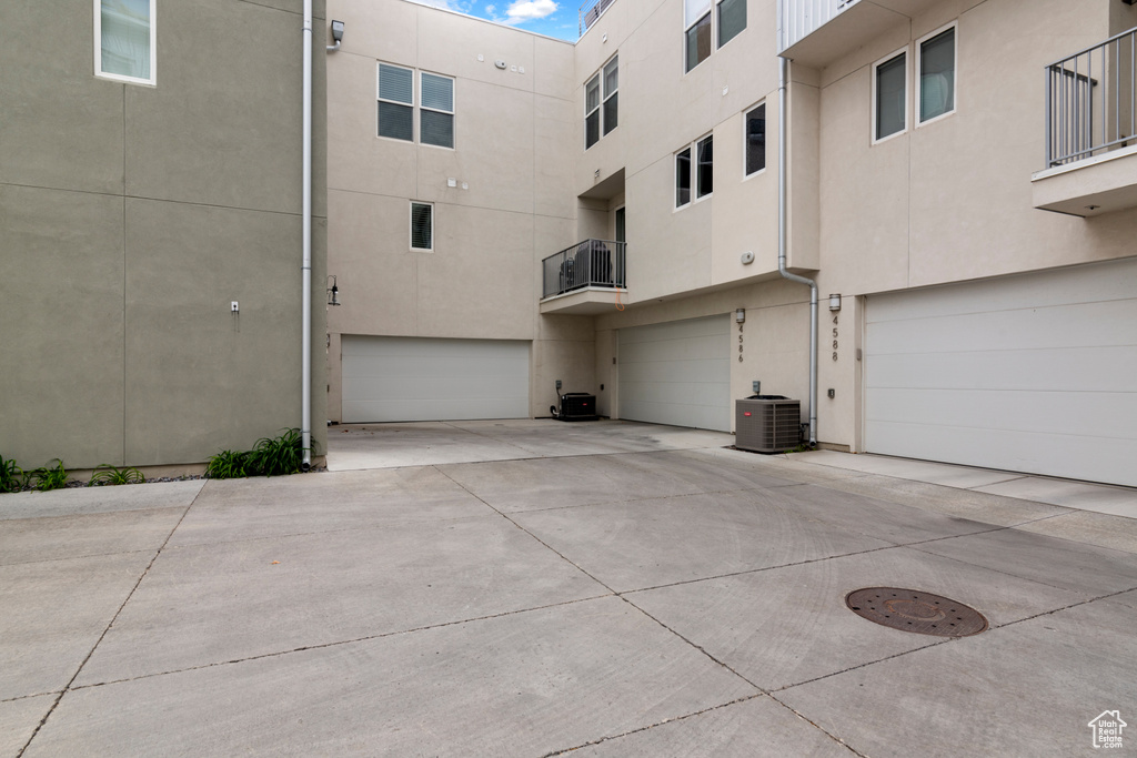View of building exterior featuring a garage, driveway, and central AC