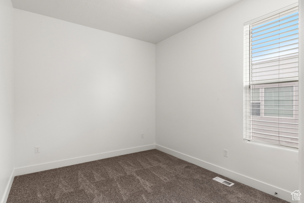 Spare room with dark colored carpet and baseboards