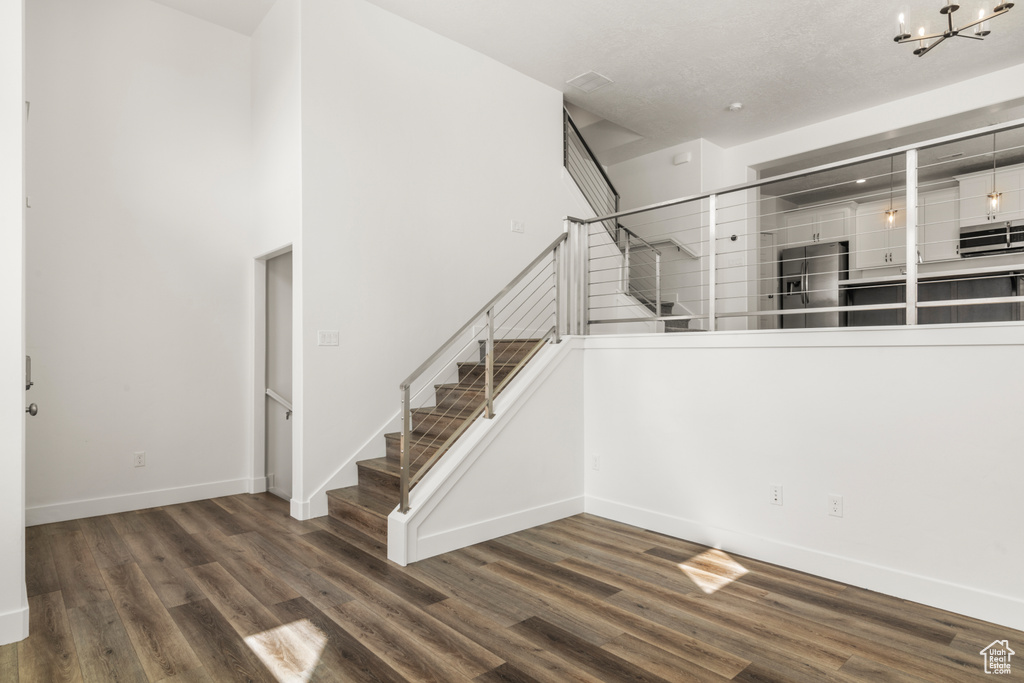 Staircase featuring a chandelier, wood finished floors, baseboards, and a towering ceiling