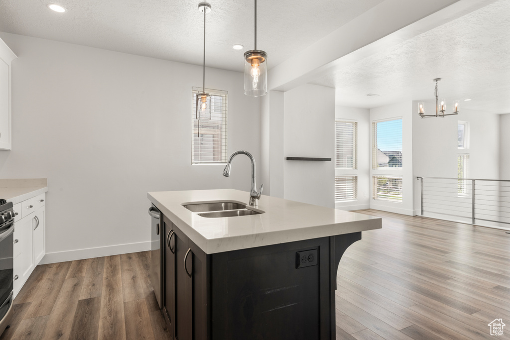 Kitchen with a sink, light countertops, light wood-type flooring, a chandelier, and recessed lighting