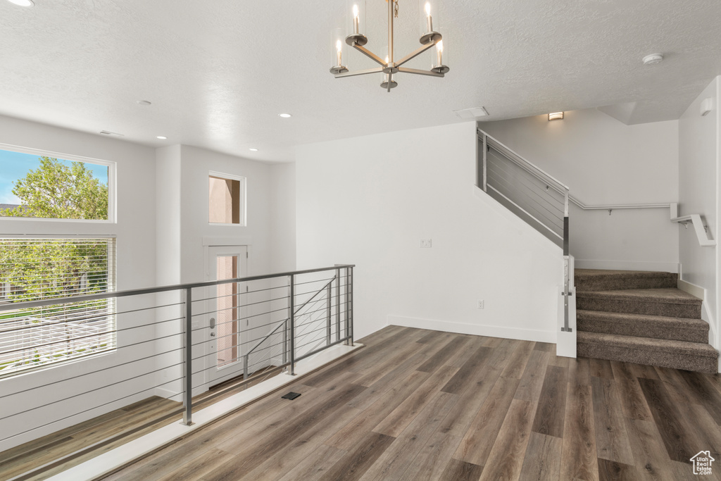 Unfurnished room with a chandelier, wood finished floors, recessed lighting, a smoke detector, and baseboards