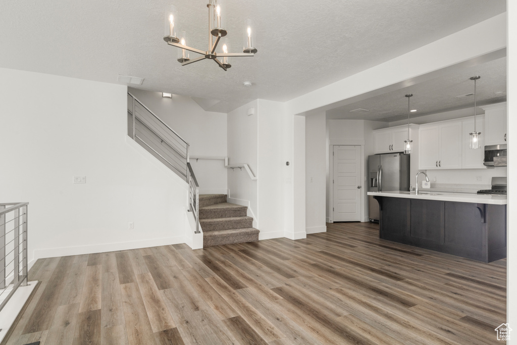Kitchen featuring stainless steel appliances, light countertops, wood finished floors, open floor plan, and a chandelier