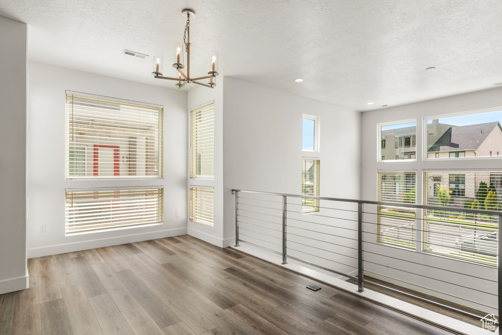 Unfurnished room with a chandelier, a textured ceiling, baseboards, wood finished floors, and recessed lighting