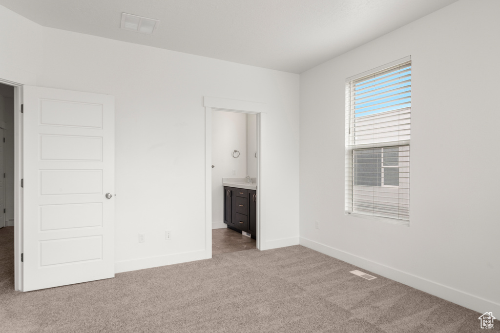 Unfurnished bedroom featuring carpet flooring, baseboards, and connected bathroom