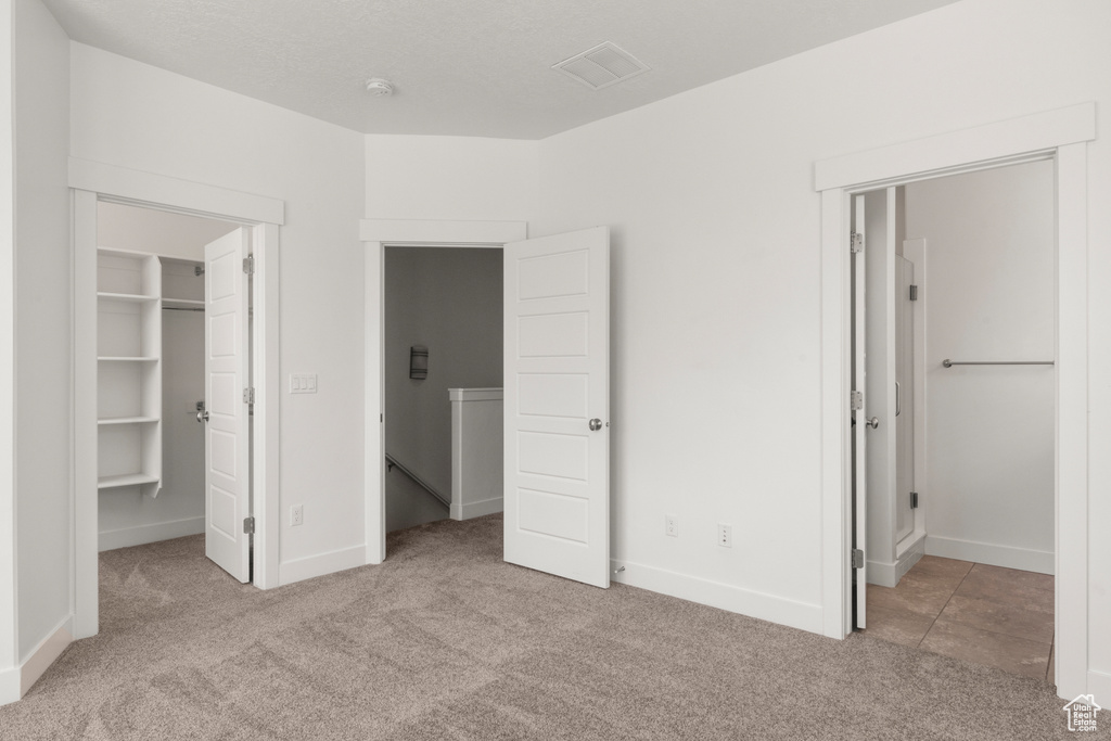 Unfurnished bedroom featuring carpet floors, a spacious closet, baseboards, and a closet