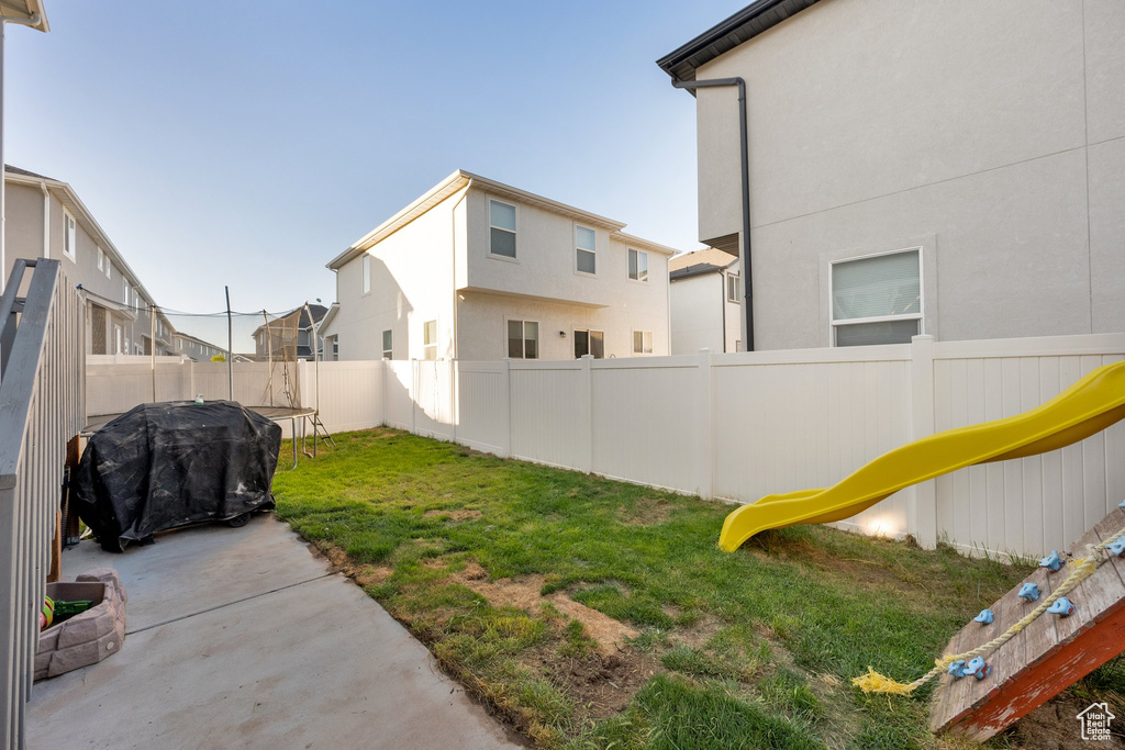 View of yard featuring a trampoline, a patio, and a residential view