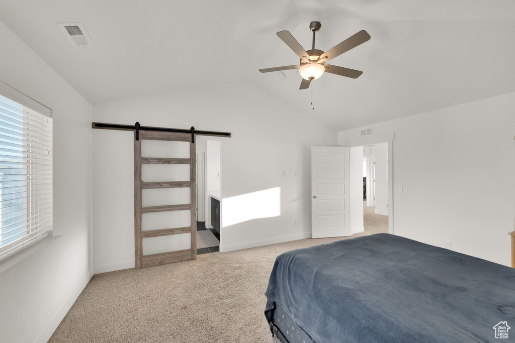 Bedroom featuring light carpet, lofted ceiling, a barn door, baseboards, and ceiling fan