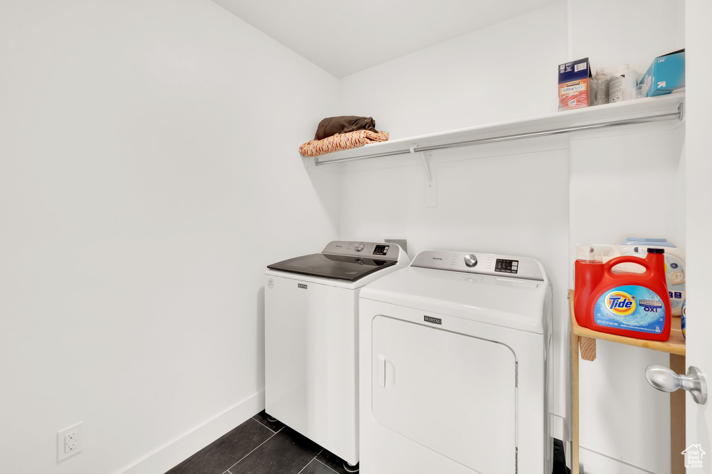 Laundry room featuring washing machine and clothes dryer, dark tile patterned flooring, and baseboards
