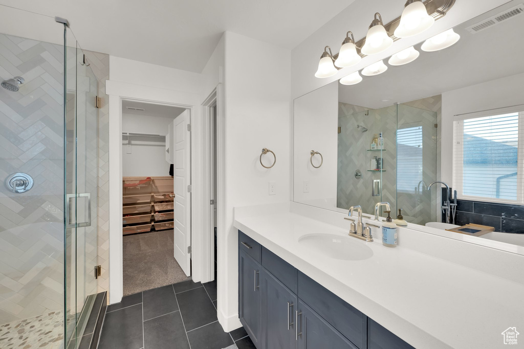 Bathroom with a shower stall, tile patterned flooring, vanity, and a spacious closet