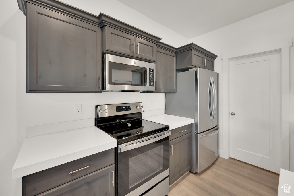 Kitchen featuring appliances with stainless steel finishes, light wood-type flooring, and light countertops